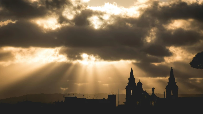 a city with dark clouds and sunlight beams in the background