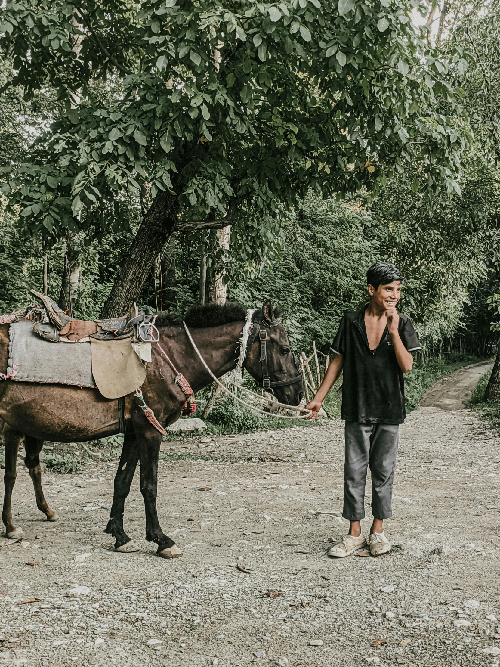 a man walks with a pony near some green trees