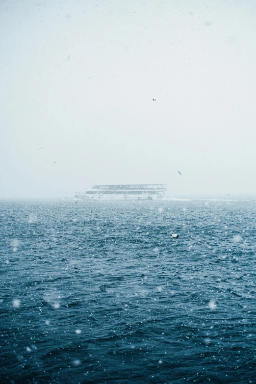 a boat floating on top of the ocean in a foggy sky