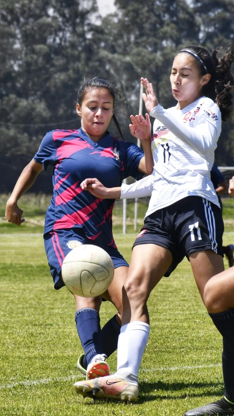 two girls on a field playing soccer during the day