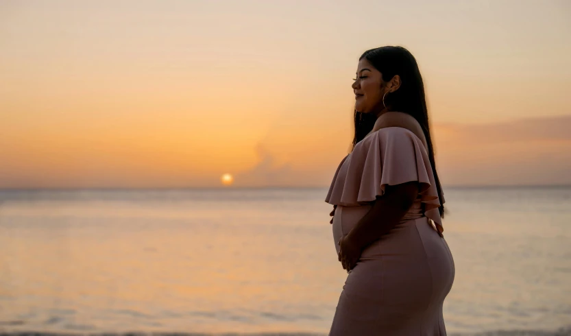 a woman is standing on the beach during sunset