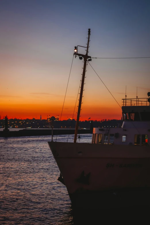 a ship sits in the water on a dark and orange day