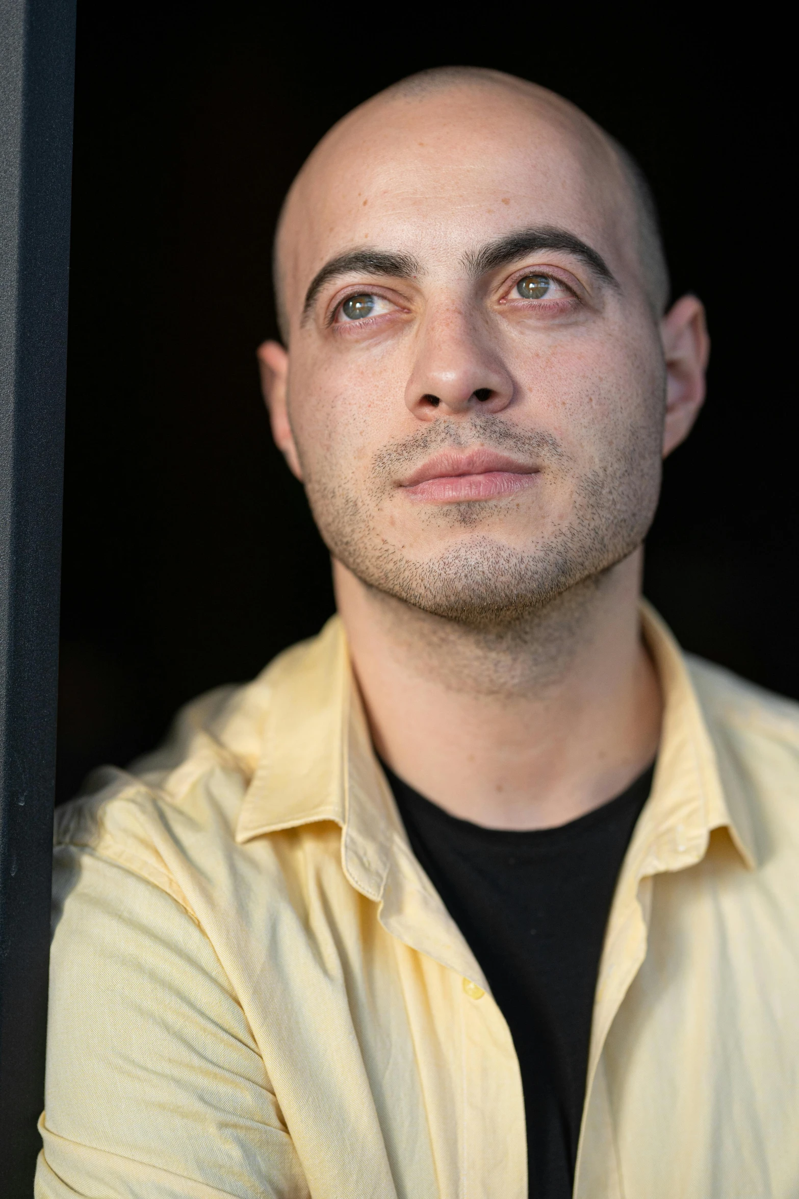 a bald headed man with blue eyes, wearing a black shirt