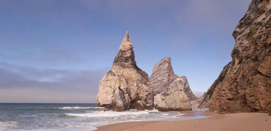 a sandy beach and large rocks next to the ocean