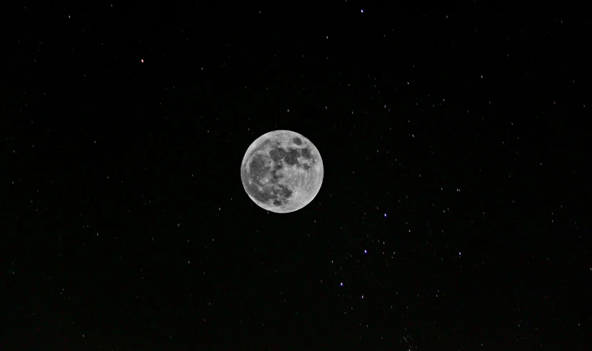 the full moon is visible in the black sky