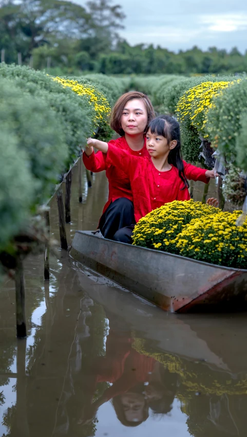 two girls in a boat that have yellow flowers inside