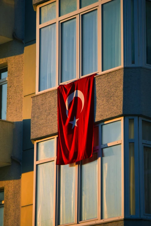 a flag hangs from the windows of an apartment building