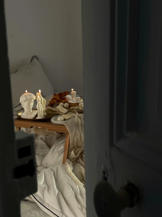 several candles are lit next to a table with white blankets on it