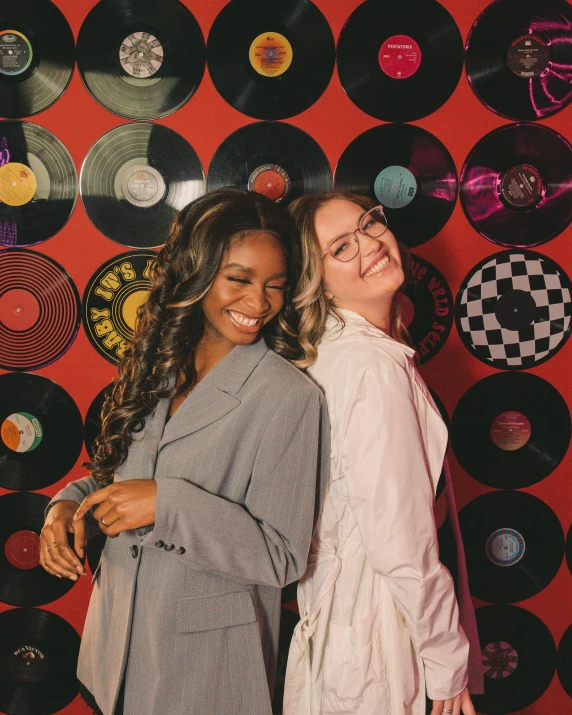 two woman in front of records wall and red background