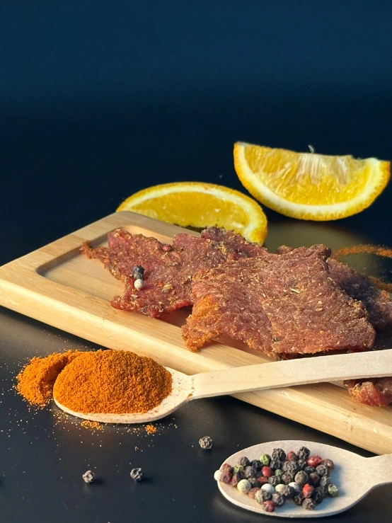 a wooden  board topped with meat next to lemon wedges