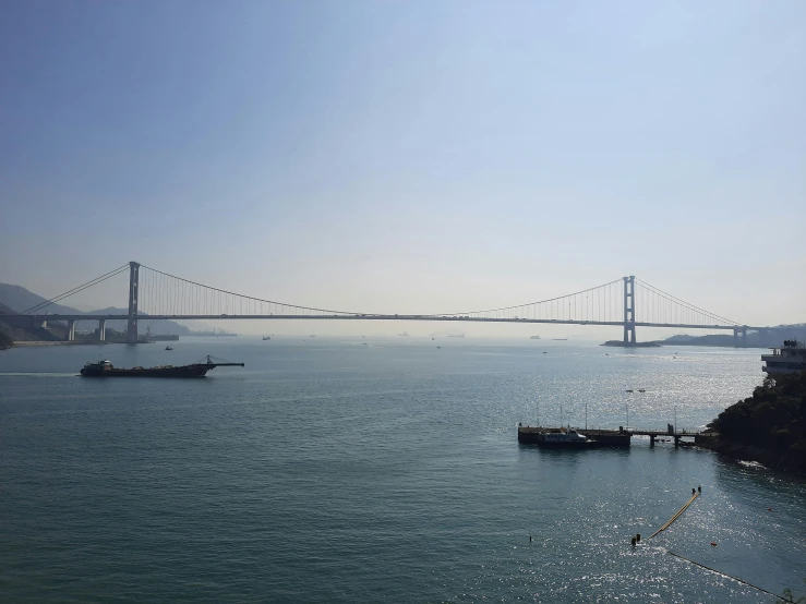 three fishing boats in the bay with a bridge in the background