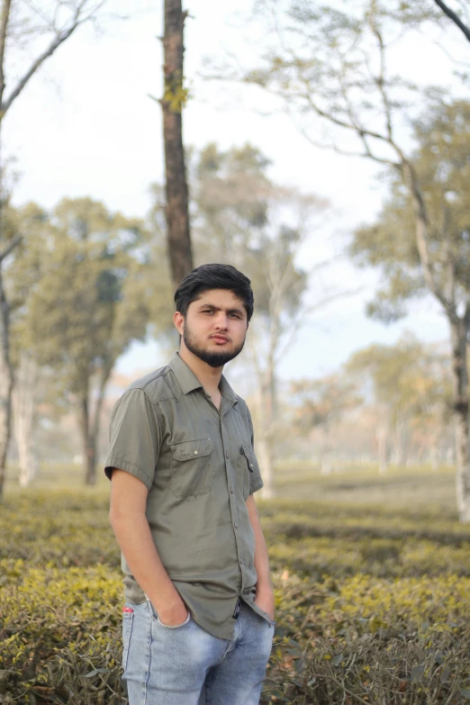 a man wearing a hat is standing in front of some bushes