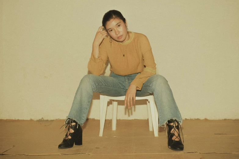 a woman is sitting on a stool wearing a sweater and heels