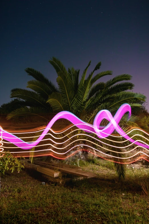 a purple light sculpture by a small bench on the grass