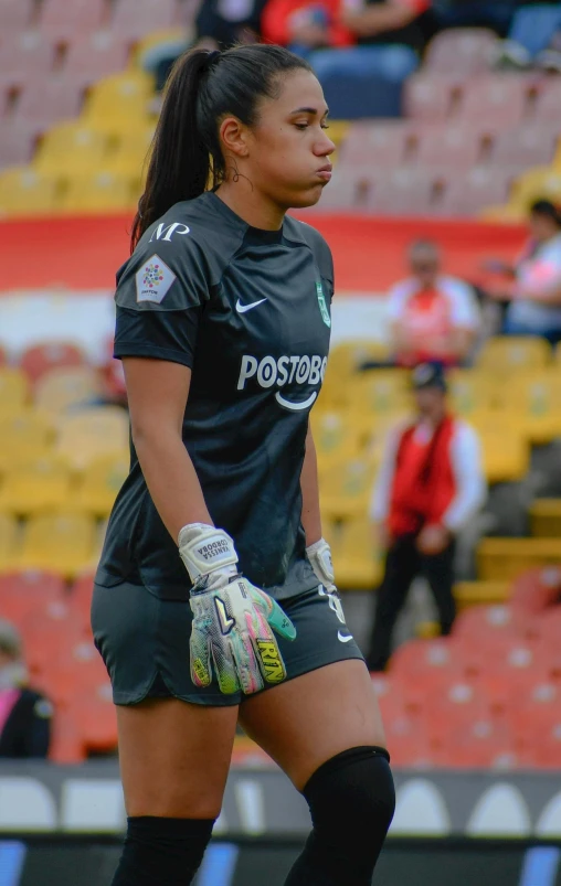 a women's soccer player with gloves on and looking over her shoulder