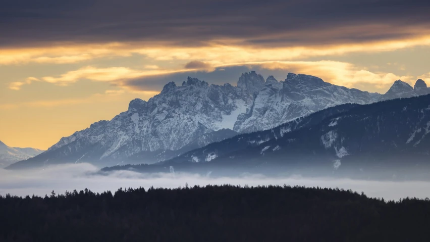 a mountain range covered in clouds and snow