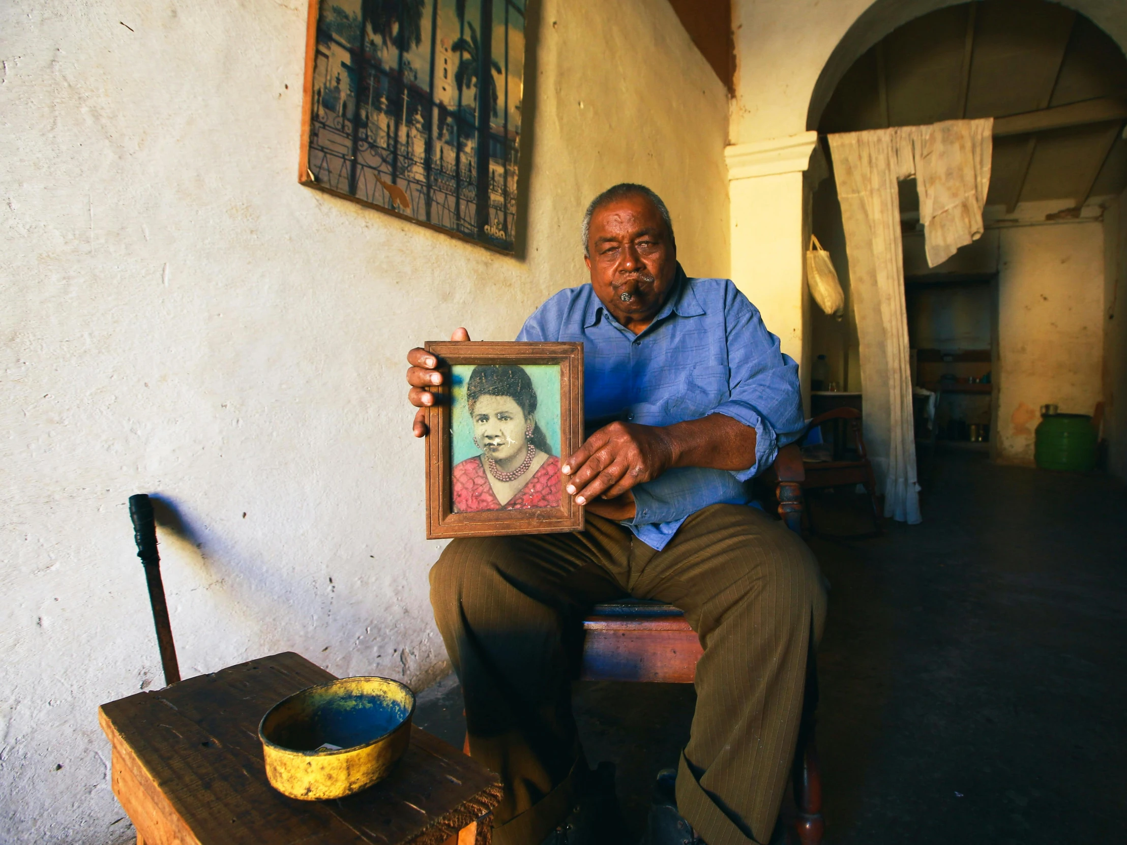 a man holds up an art work with a portrait on it