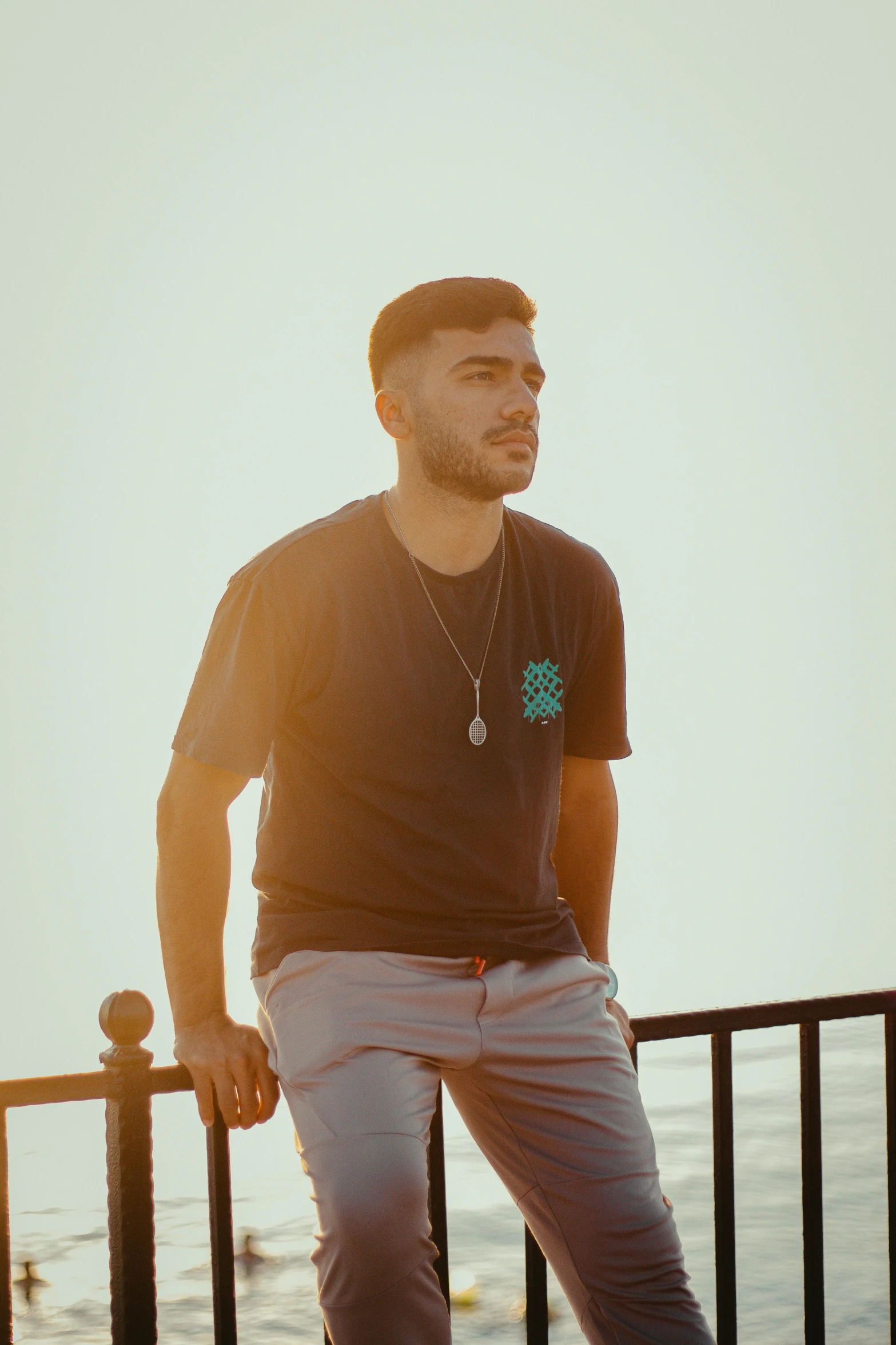 a man is standing on a railing next to the ocean