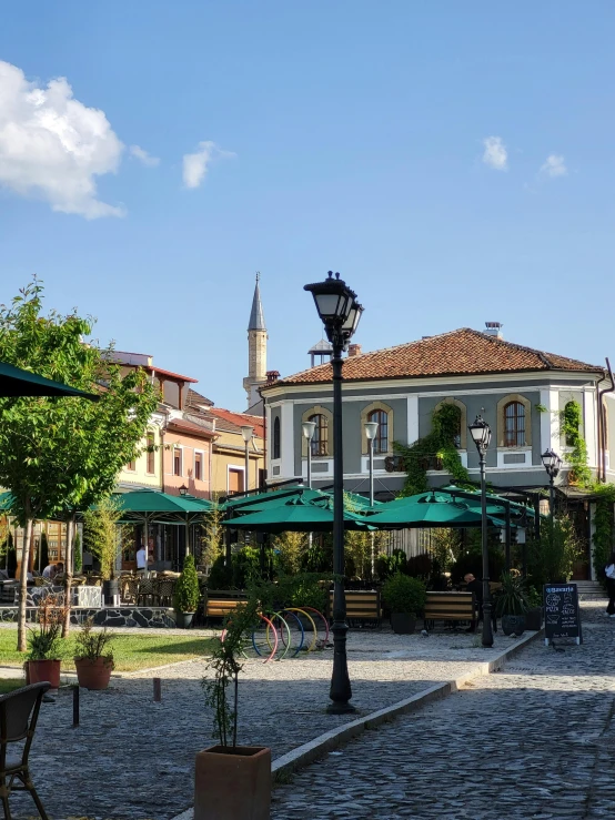 the town square has tables and umbrellas with benches around it