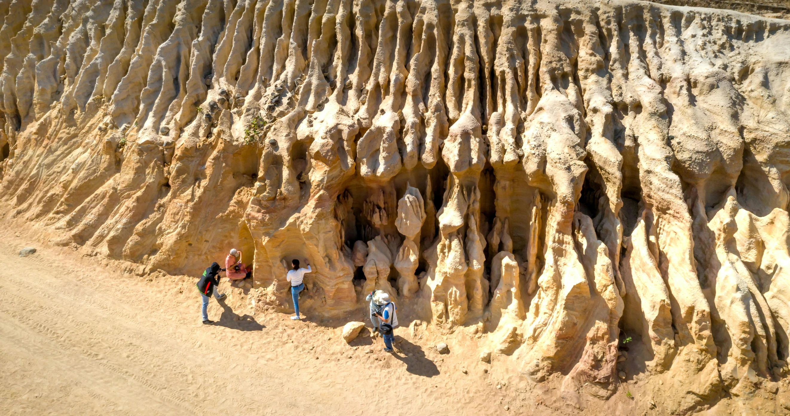 three people looking at large carved formations in desert