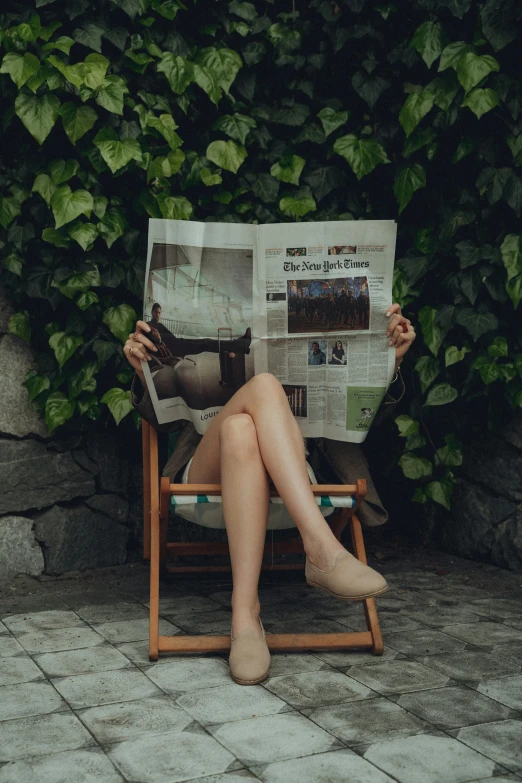 a person reading a newspaper in a chair