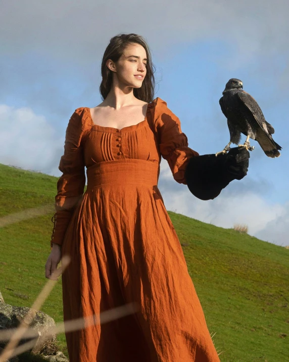 a woman in an orange dress holds a bird