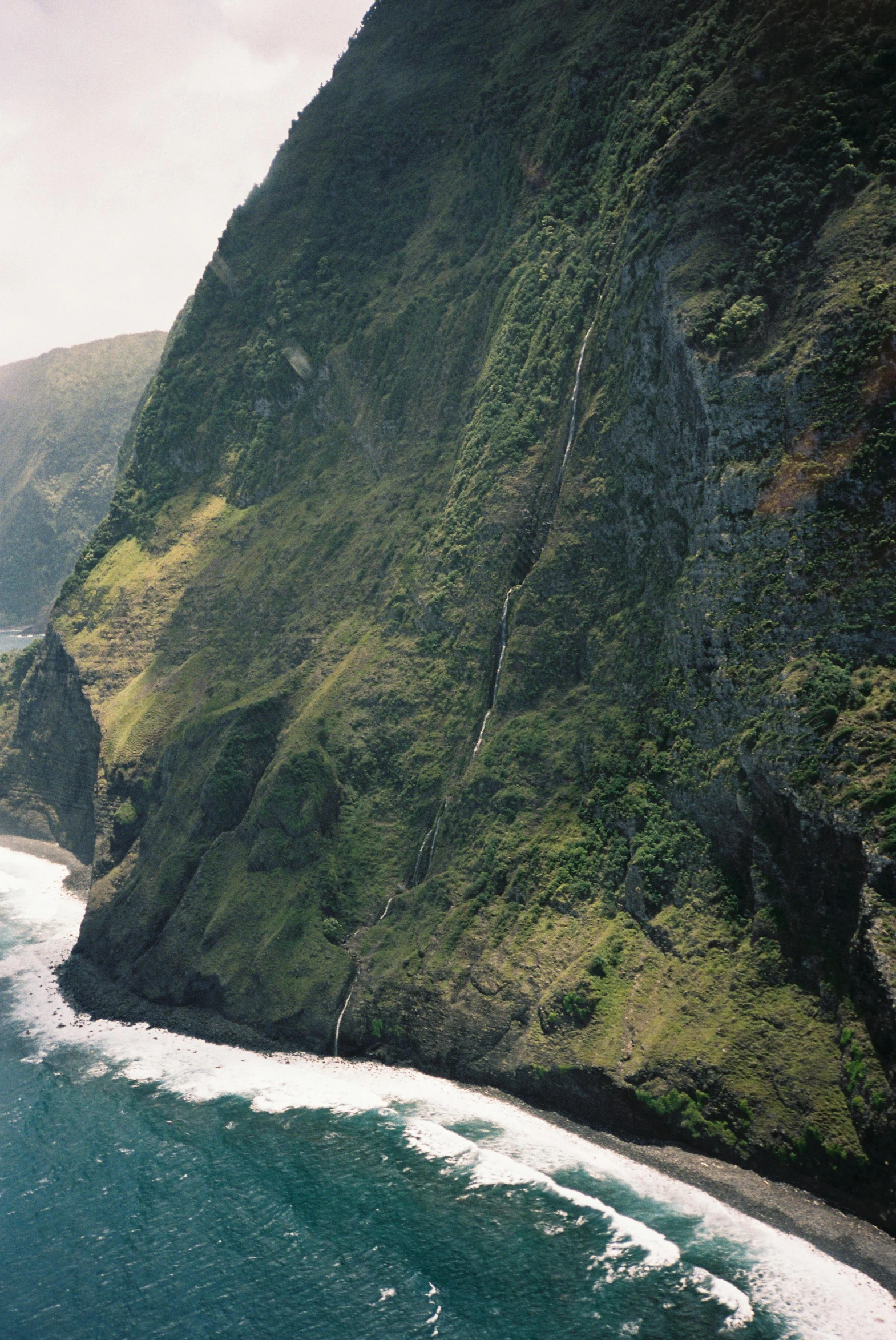 a grassy mountain next to the ocean, with very steep cliffs on both sides