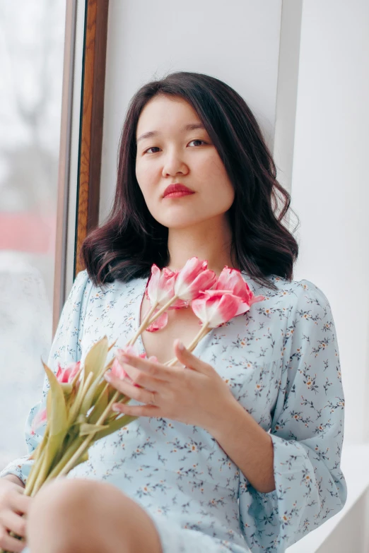 a woman wearing a blue dress holding flowers