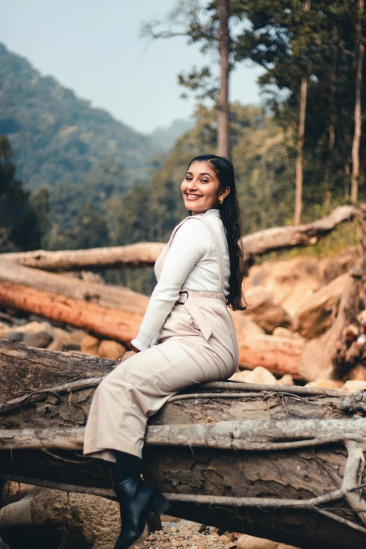 a beautiful woman sitting on top of a log