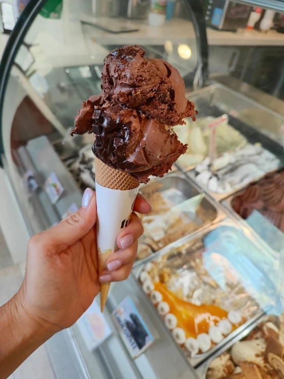 a hand holding an ice cream sundae cone