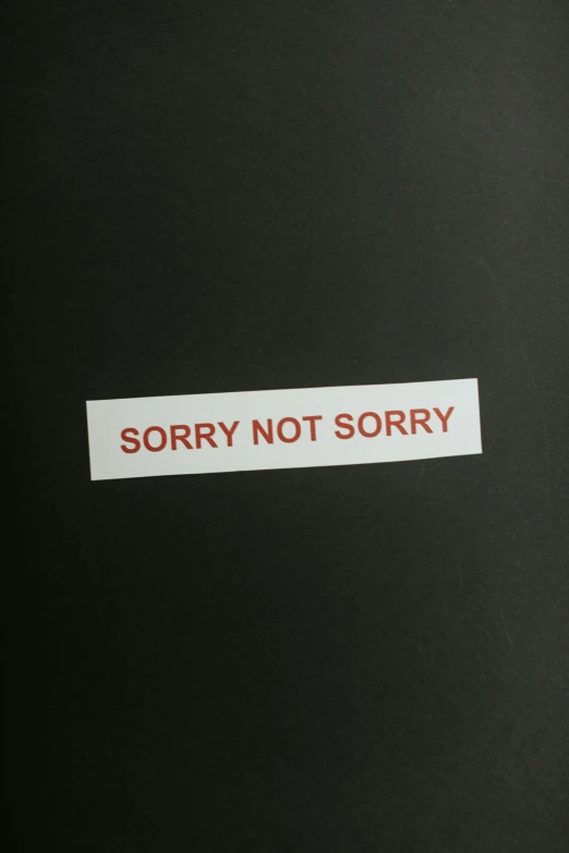 an inscription on a black sheet that says sorry not sorry