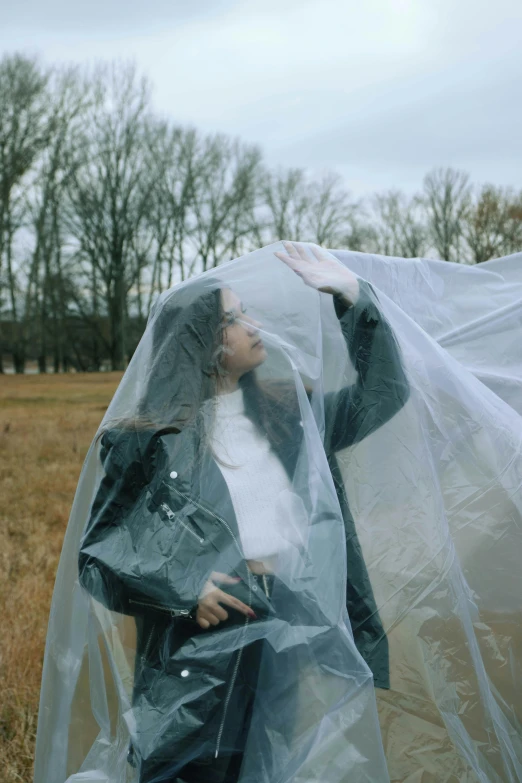 a woman standing under a plastic wrap and looking outside