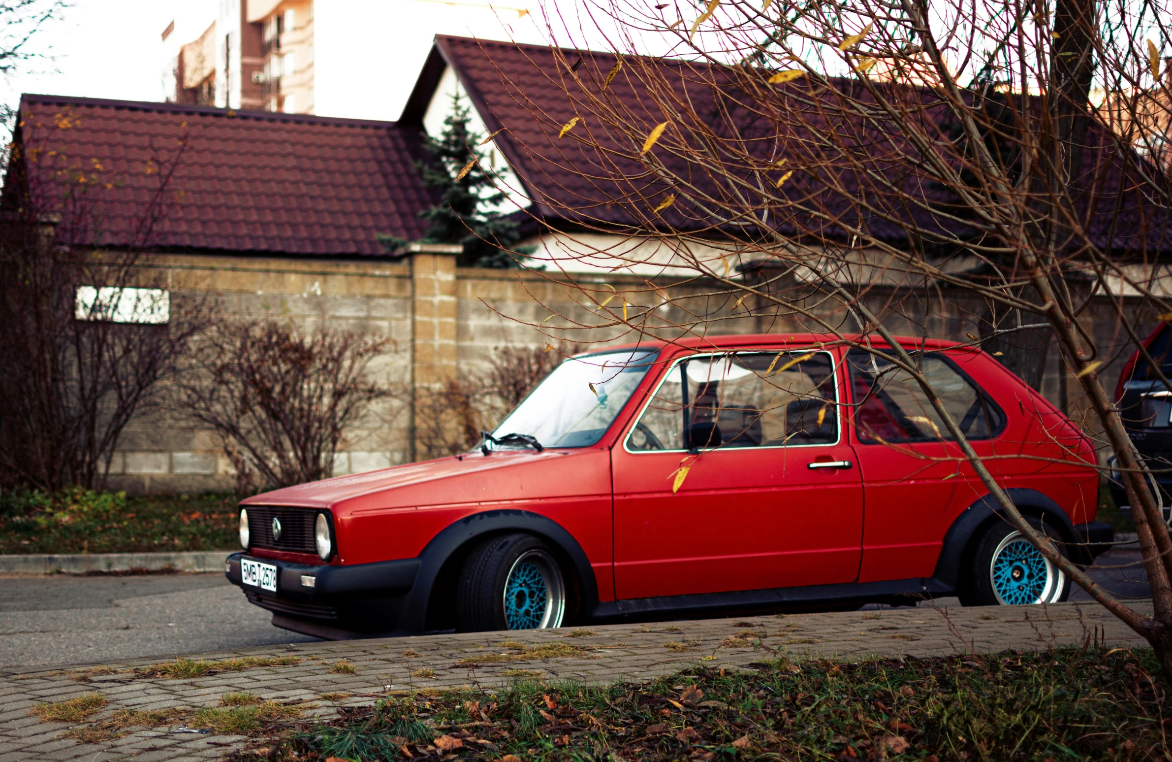 a red car parked by the curb in front of a house