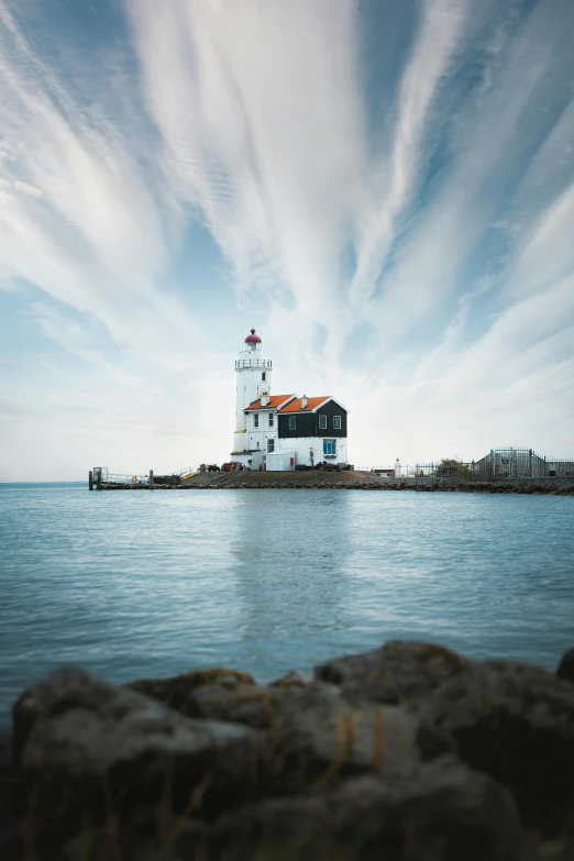 a white lighthouse is standing on the edge of a sea