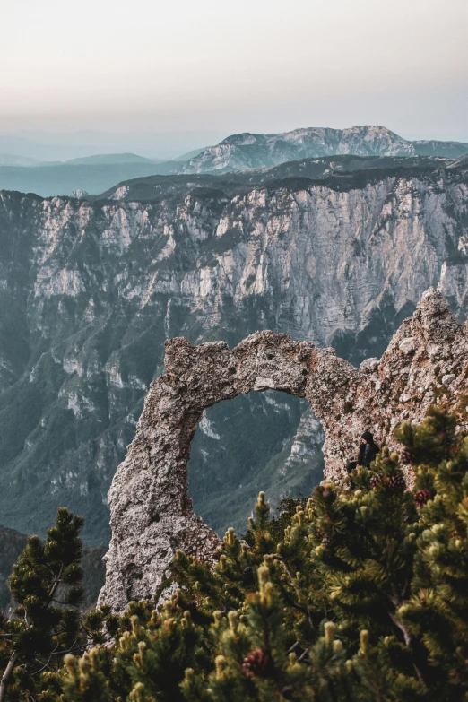 a rock arch sits on the edge of a mountain