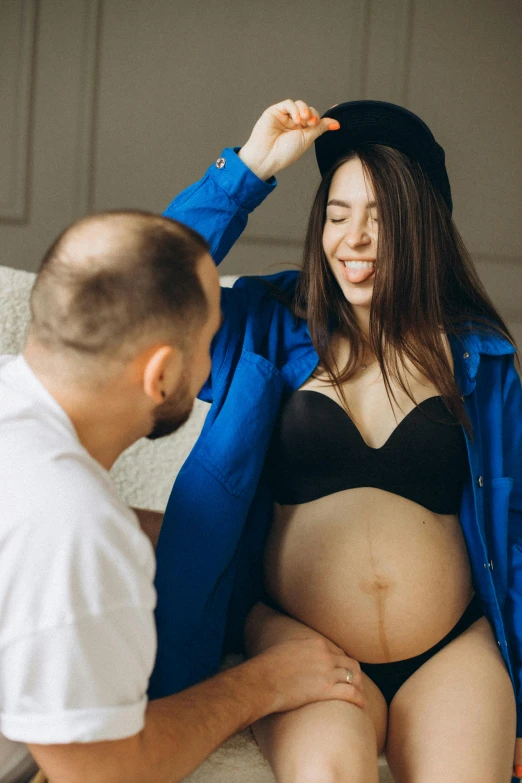 a young pregnant woman in a black lingerie sits next to a man as they look at each other