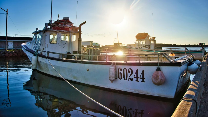 a small white boat sitting next to another boat