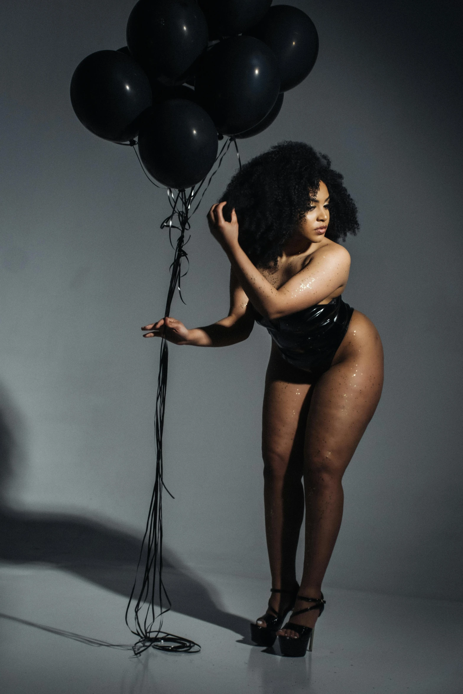 a woman in a lingerie posing with a bunch of balloons