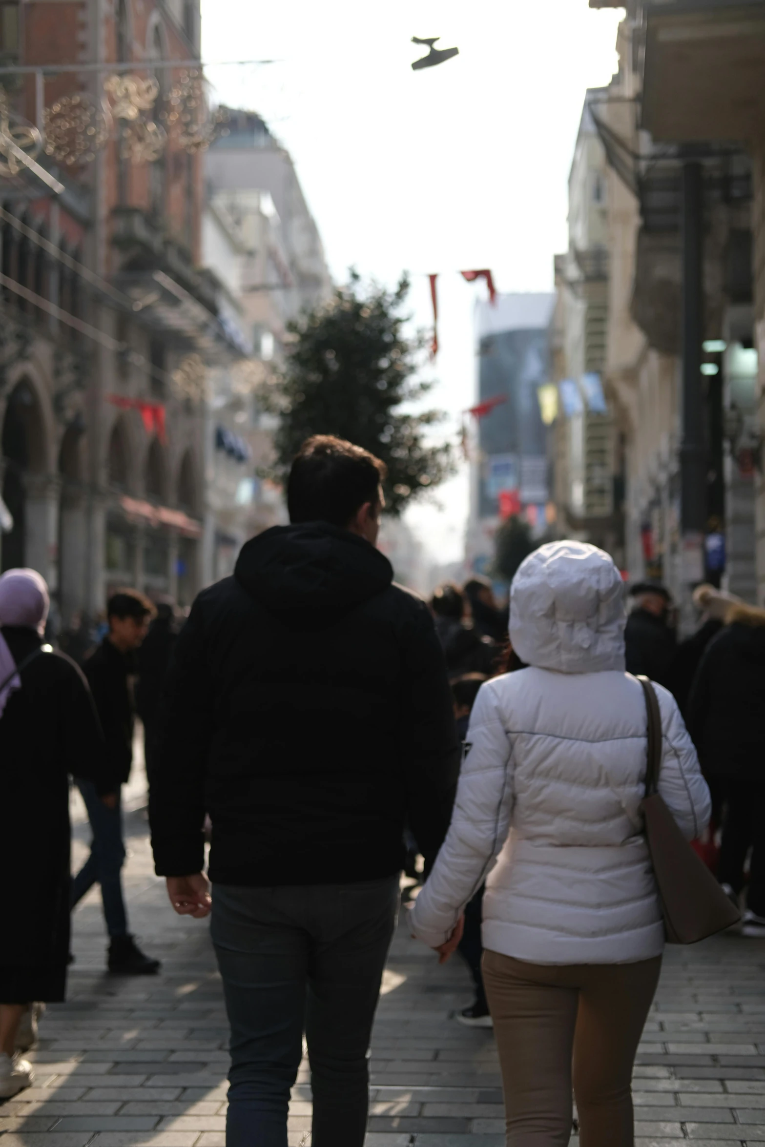 a man and woman walking down a street next to tall buildings