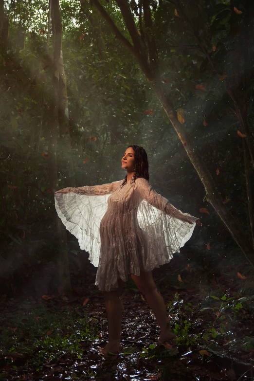 a woman is posing in the woods holding her arms out to the sides