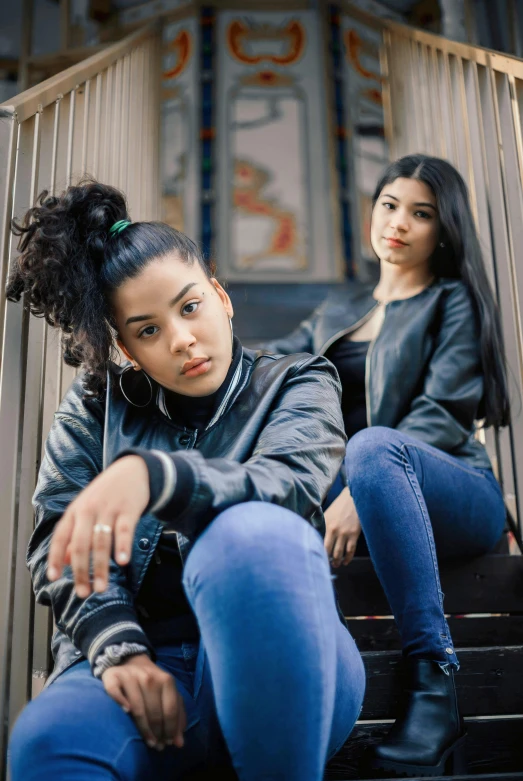 a young woman in a black jacket sitting next to another girl