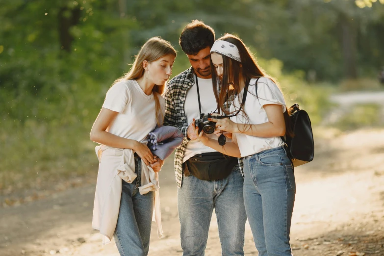 three friends looking at their phone while on a path