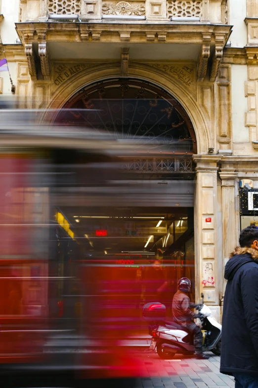 blurry image of people walking past a red bus