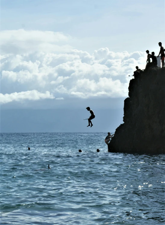 man jumping off the edge of a cliff into the ocean