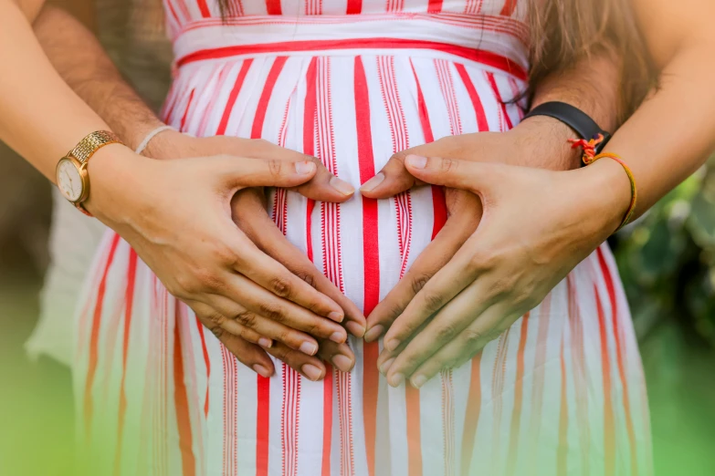 two hands holding on to the belly of a pregnant woman