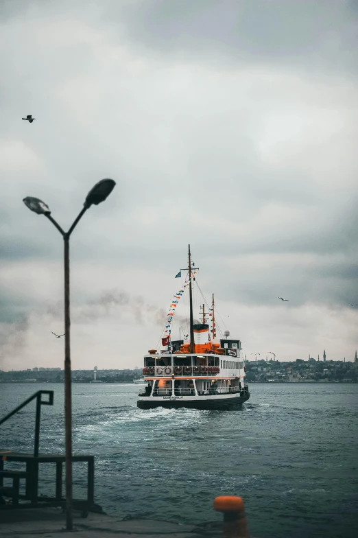 a ferry boat on the water passing under a cloudy sky