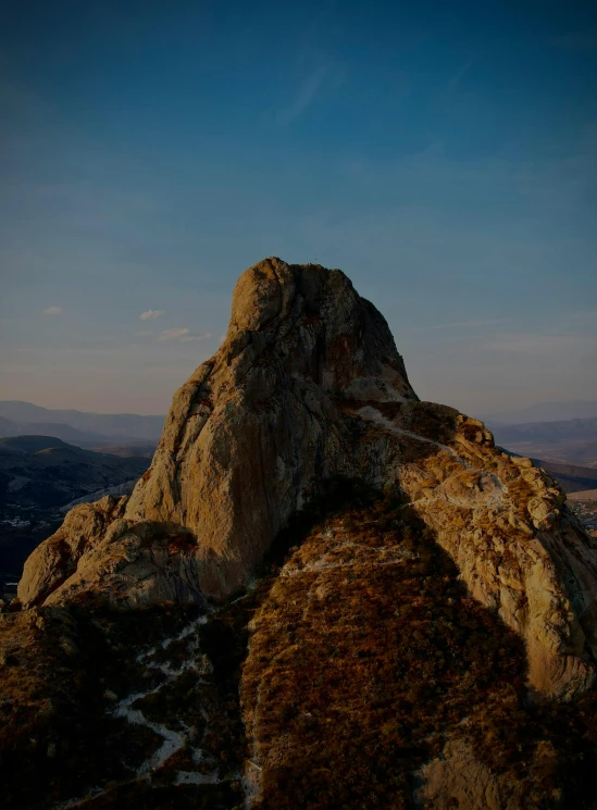 the top of a very tall rocky mountain with a bird flying over it