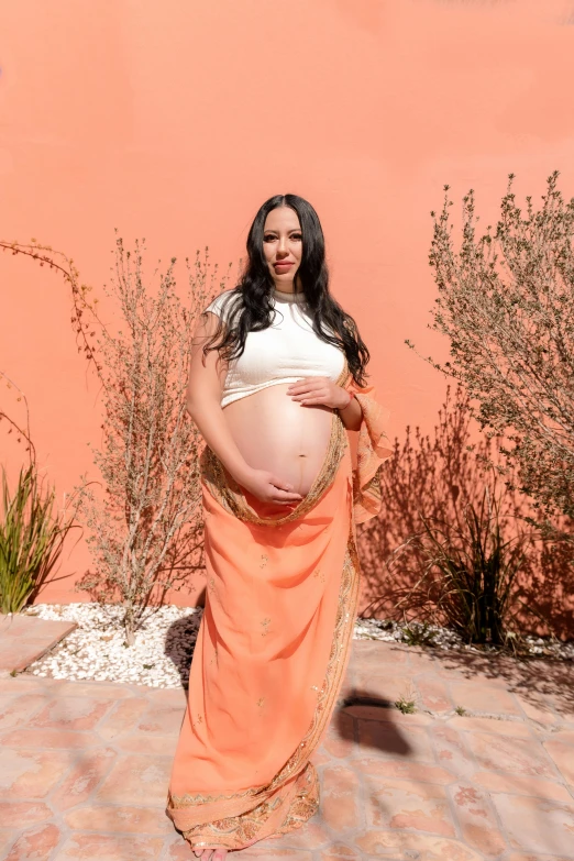 a pregnant woman poses in an orange skirt