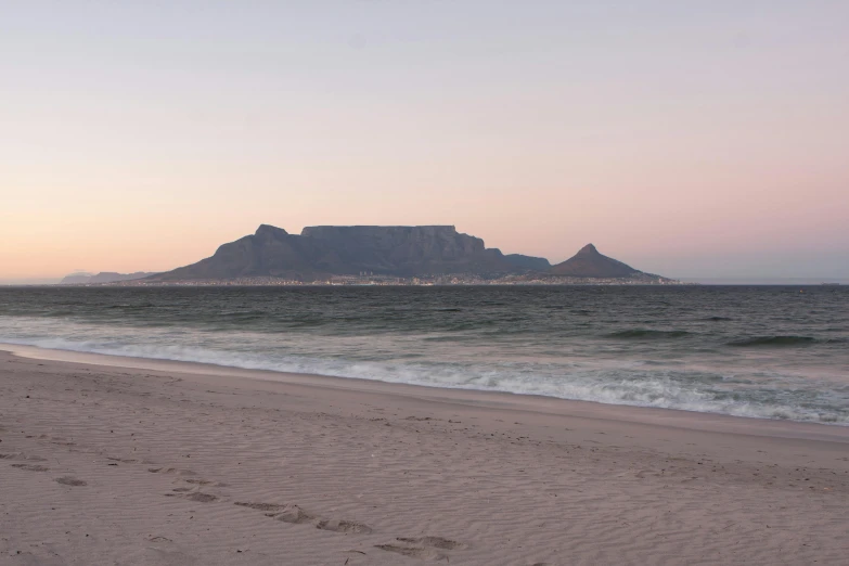 the sea and sand at the beach have a long line of footprints