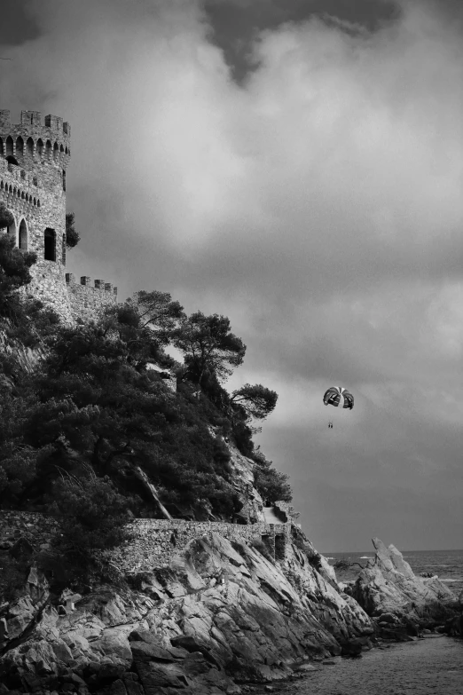 a black and white picture of an old tower on the side of a rock